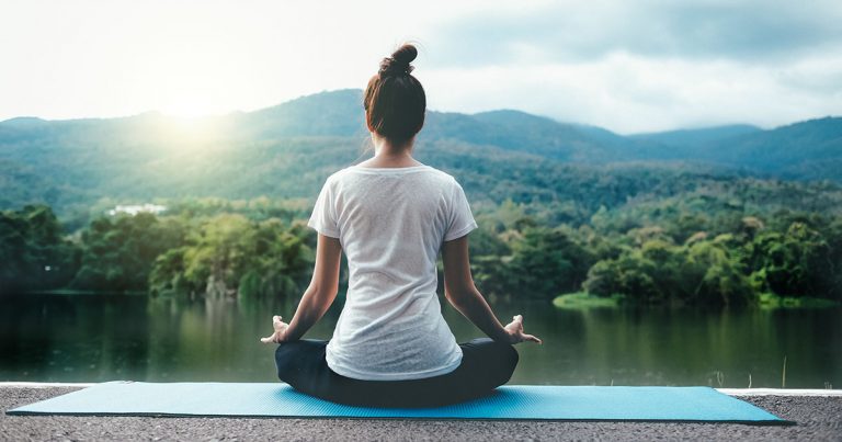 Young woman doing yoga in morning park for Relaxing . Wellness and Healthy Lifestyle.